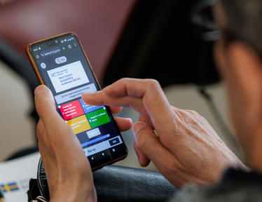 Photograph of hands holding a smartphone displaying a colorful app interface.